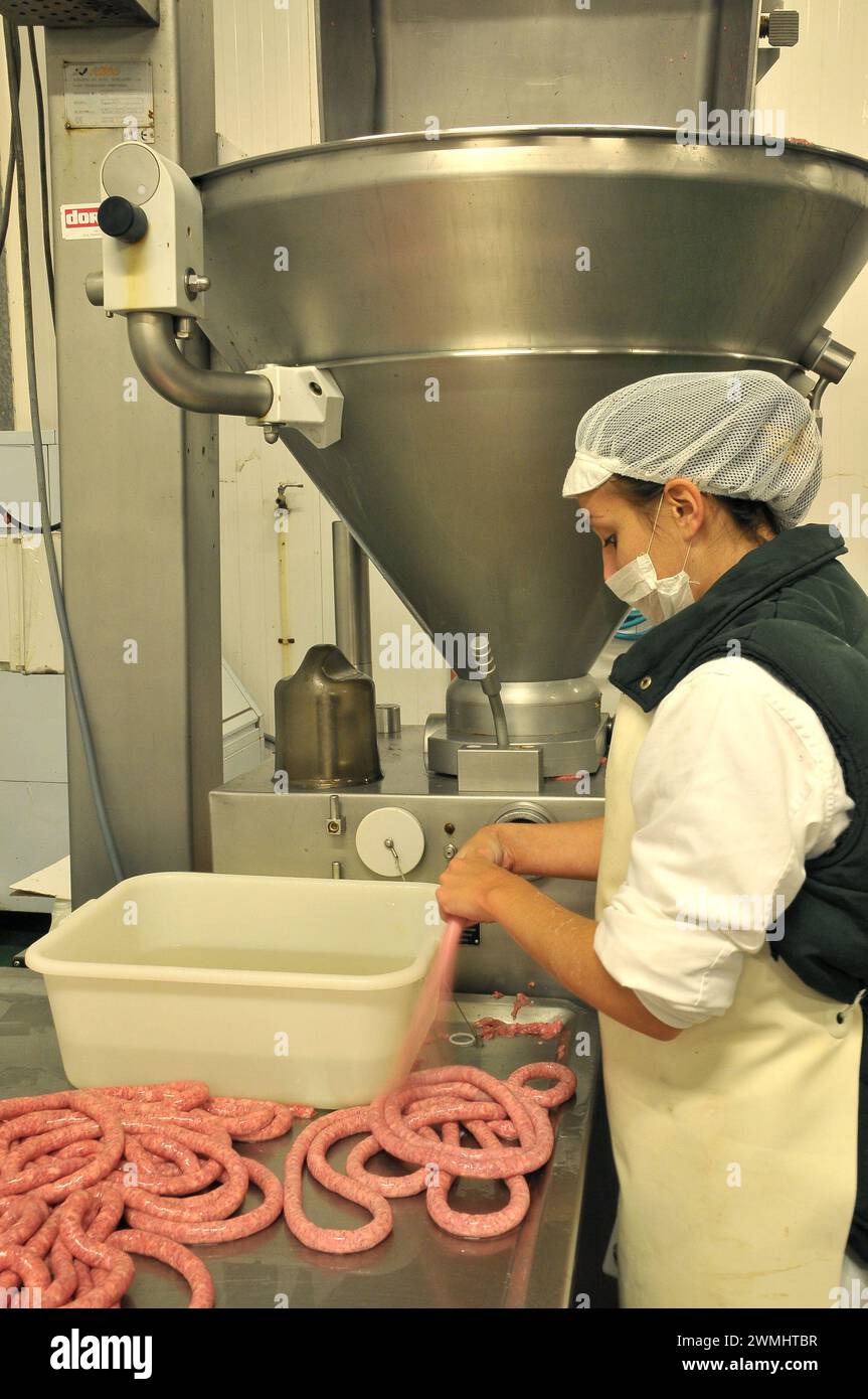 Woman working on the sausage process in a factory Stock Photo
