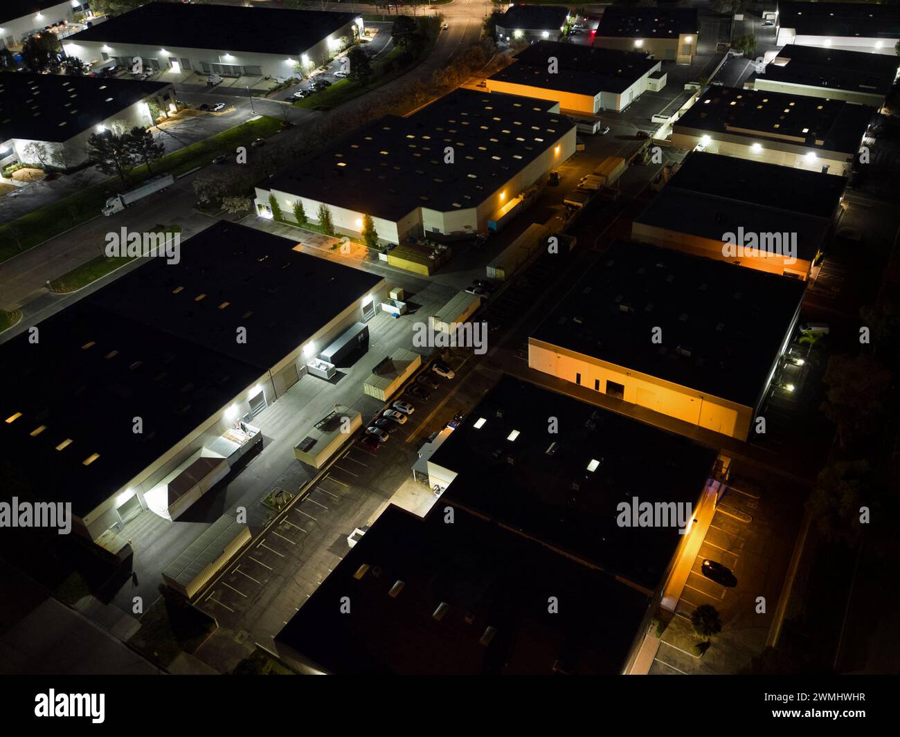 Nondescript warehouses and office buildings of an industrial business park are shown from an overhead view at night. Stock Photo