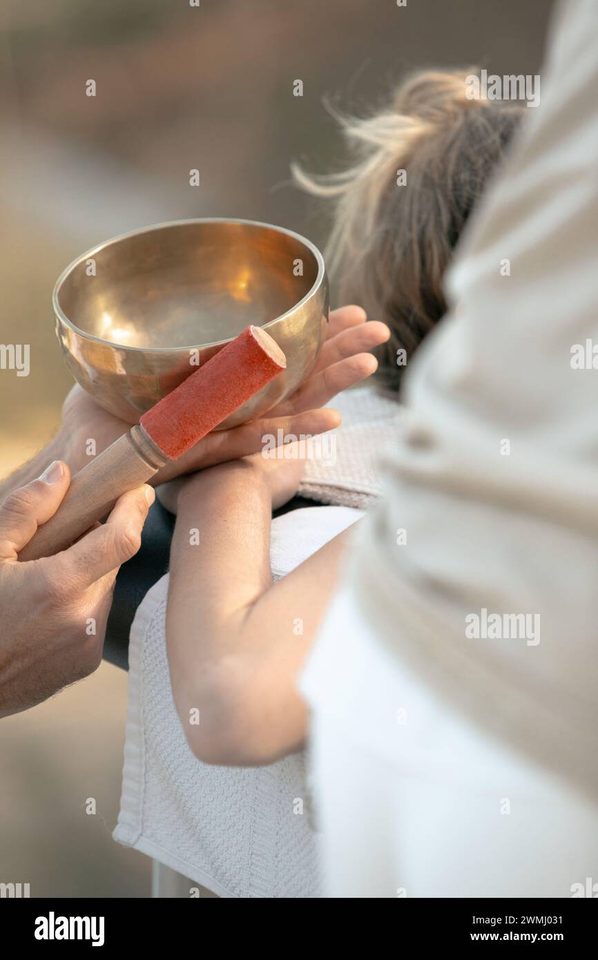 Intimate Sound Healing Session with a Tibetan Singing Bowl Being Played on a Client's Back for Chakra Balancing and Mindfulness Stock Photo