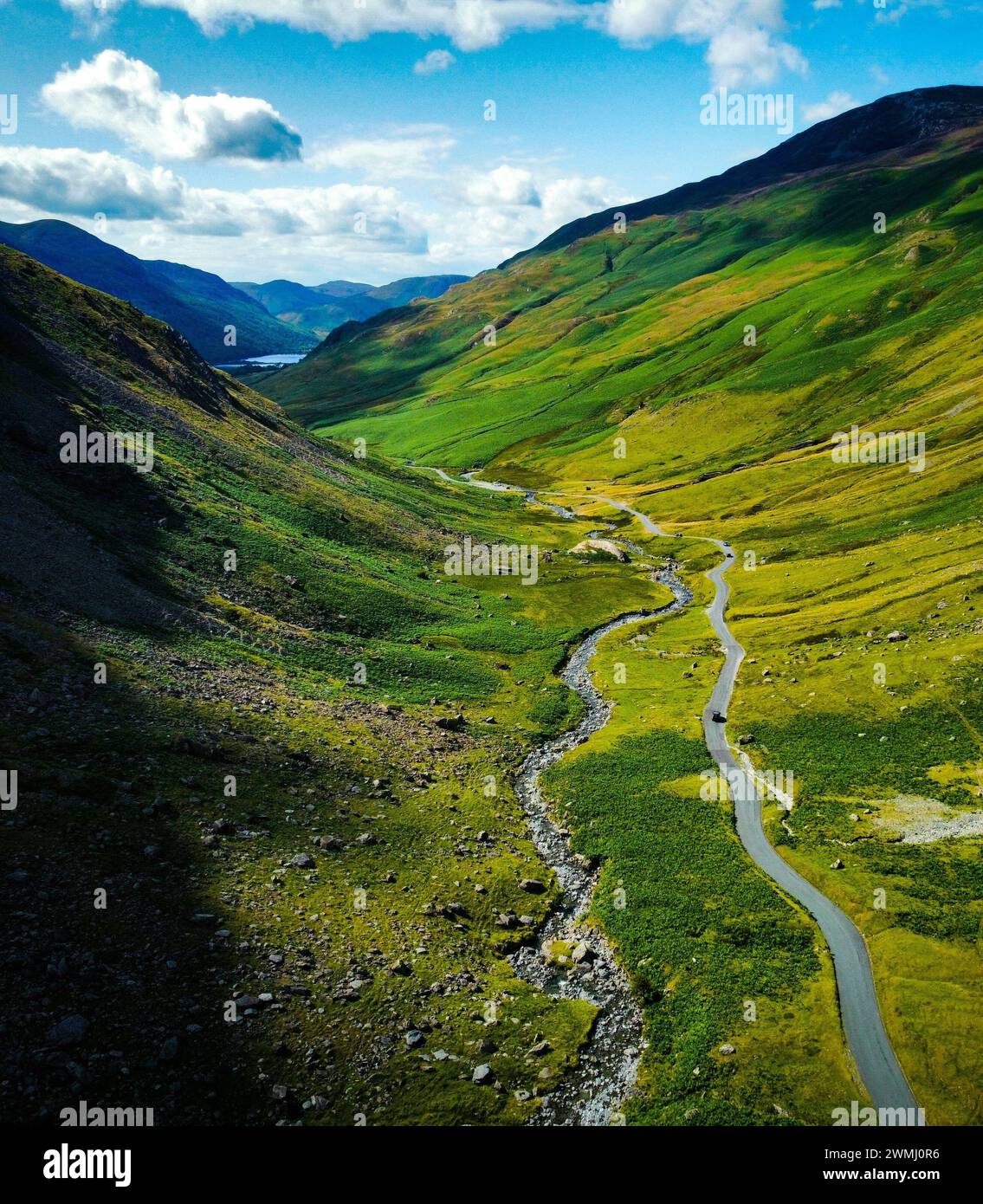 A scenic road winding through lush green hills in a valley Stock Photo ...