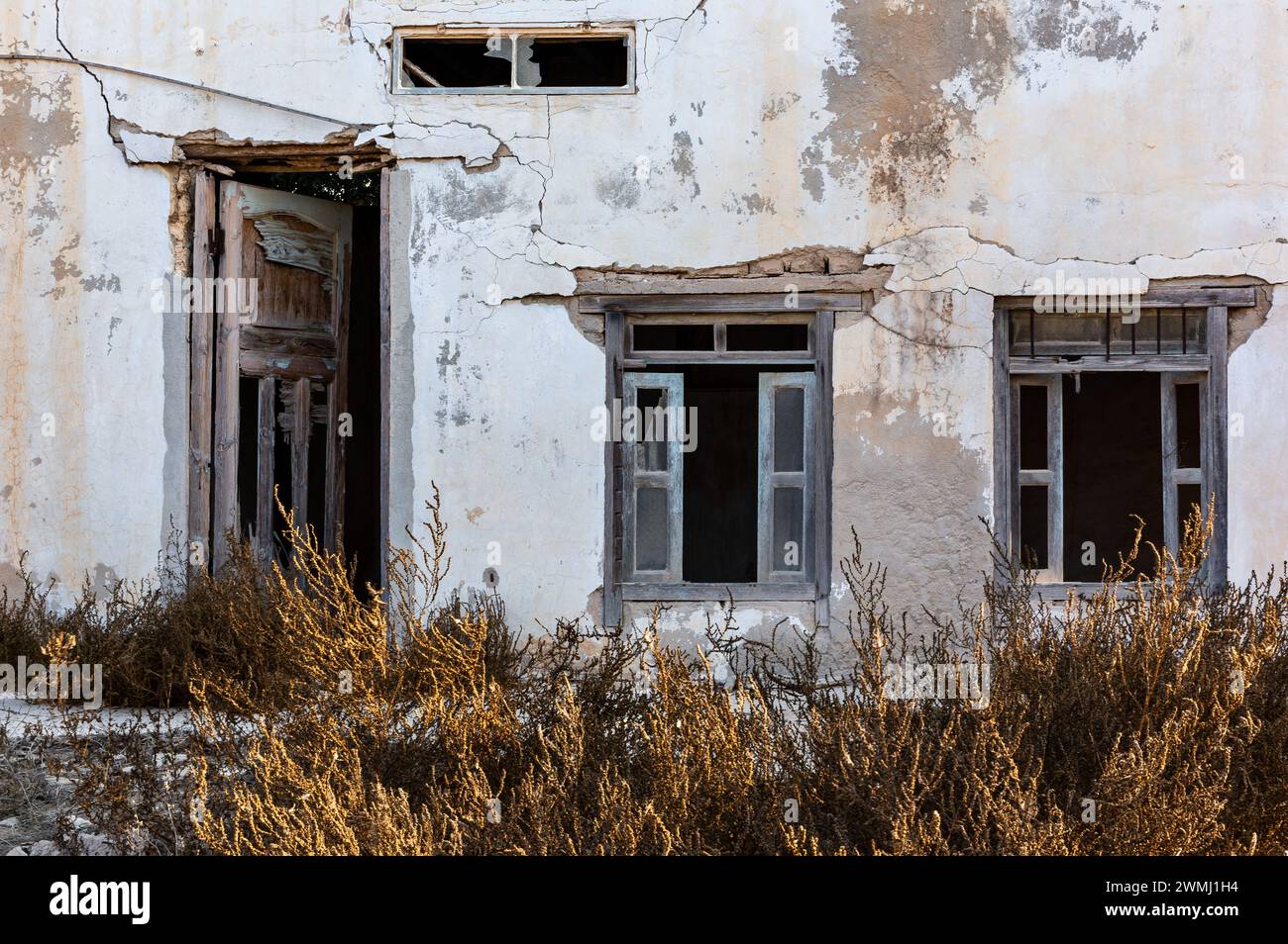 Neglected building facade with broken windows, blue window shutters and