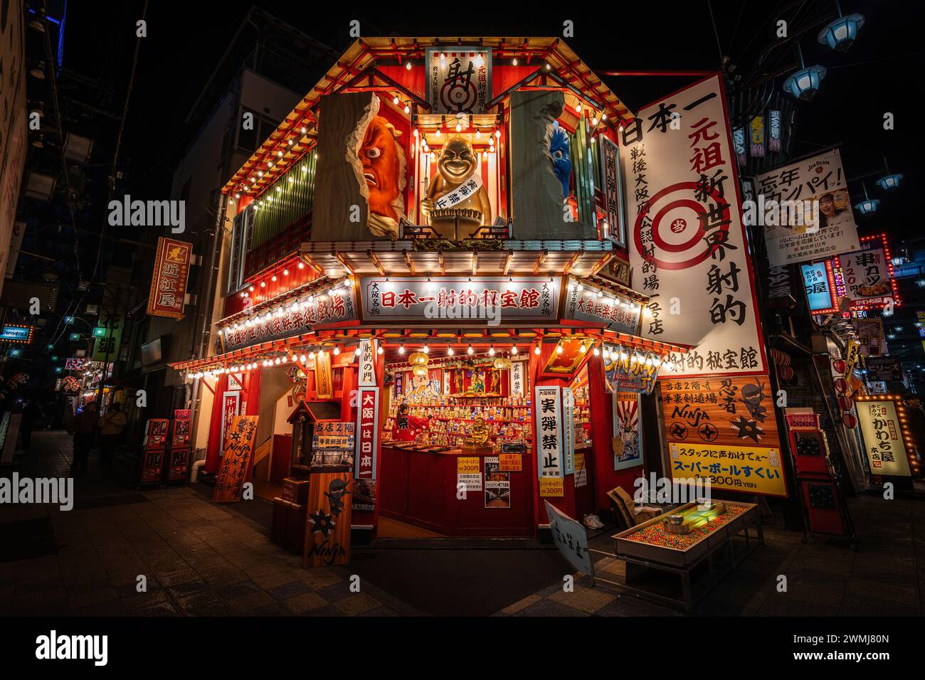 Shooting gallery illuminated at night in the Shinsekai 'New World' district of Osaka, Japan. Stock Photo
