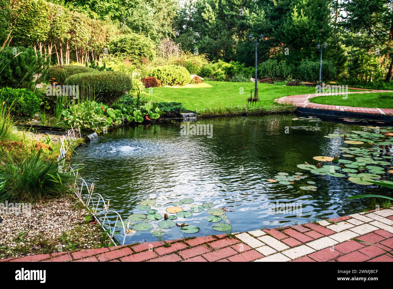 Awe Water Garden  (Pond)next to cottage in prosperous village next to Khimki in  Moscow Oblast with small bridge witg metal railngs. Also 2 artificial Stock Photo