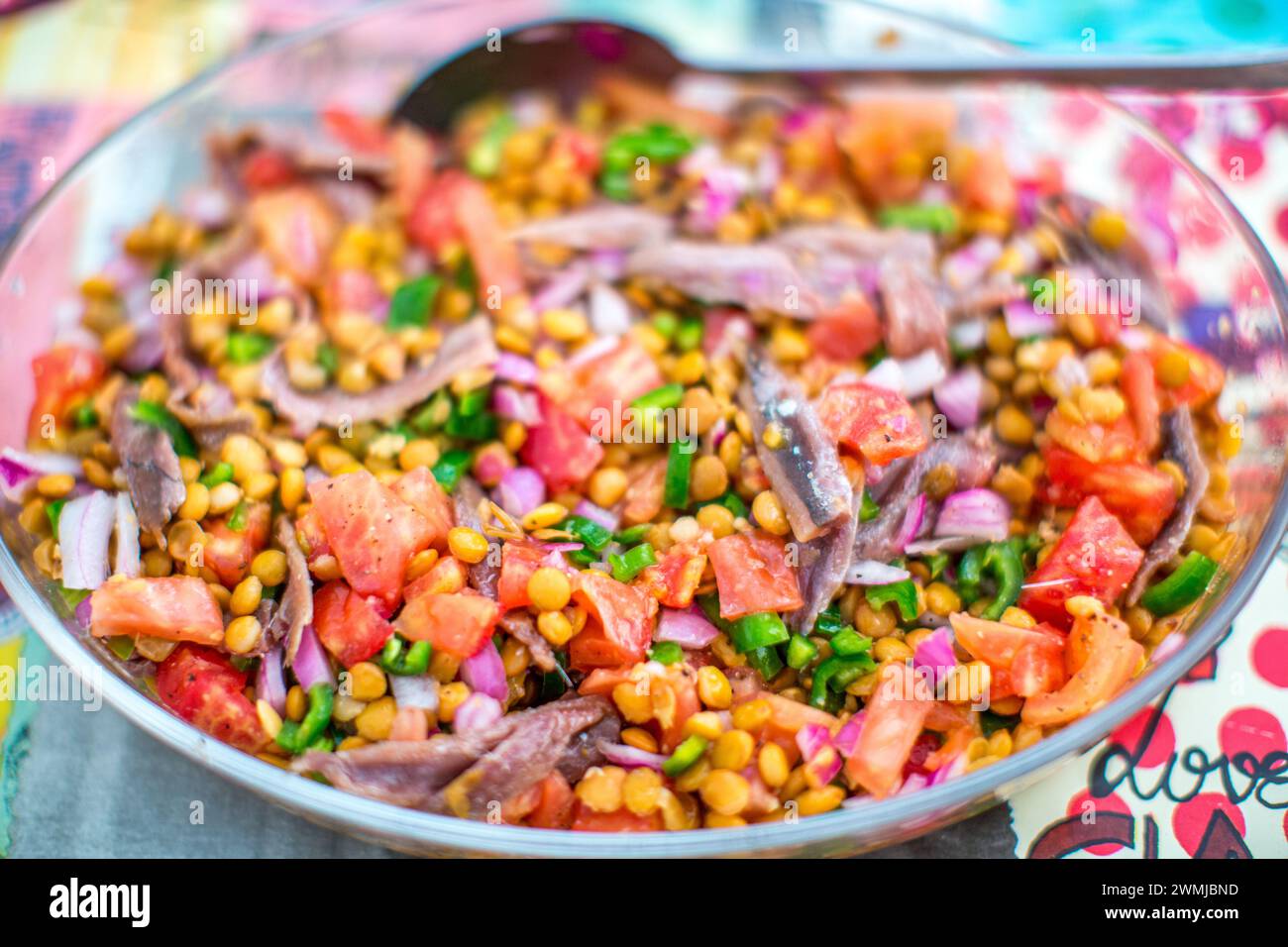 A vibrant bowl of lentil salad mixed with chunks of tomato, diced green