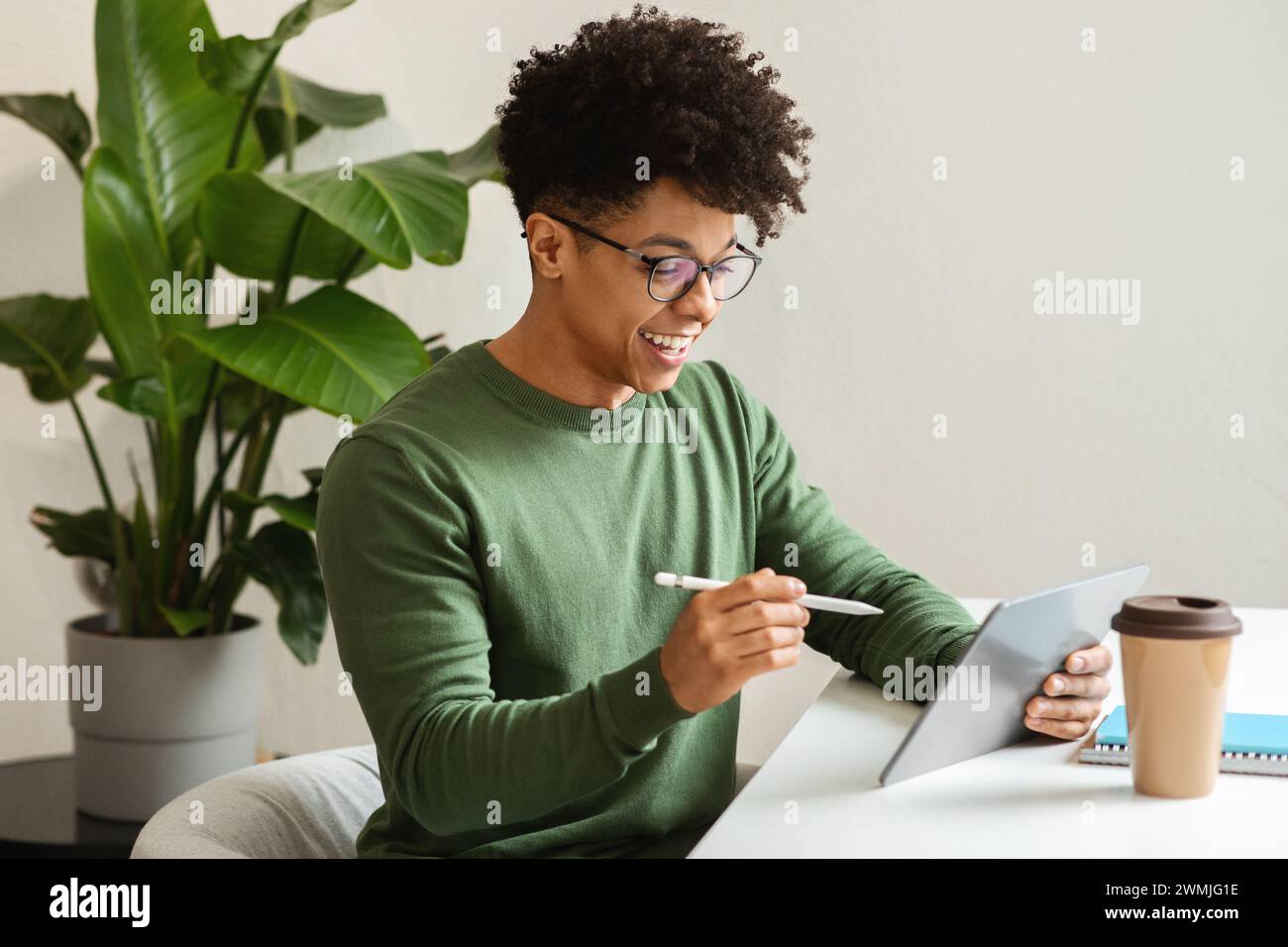 Stylish african american guy using digital tablet, drinking coffee Stock Photo