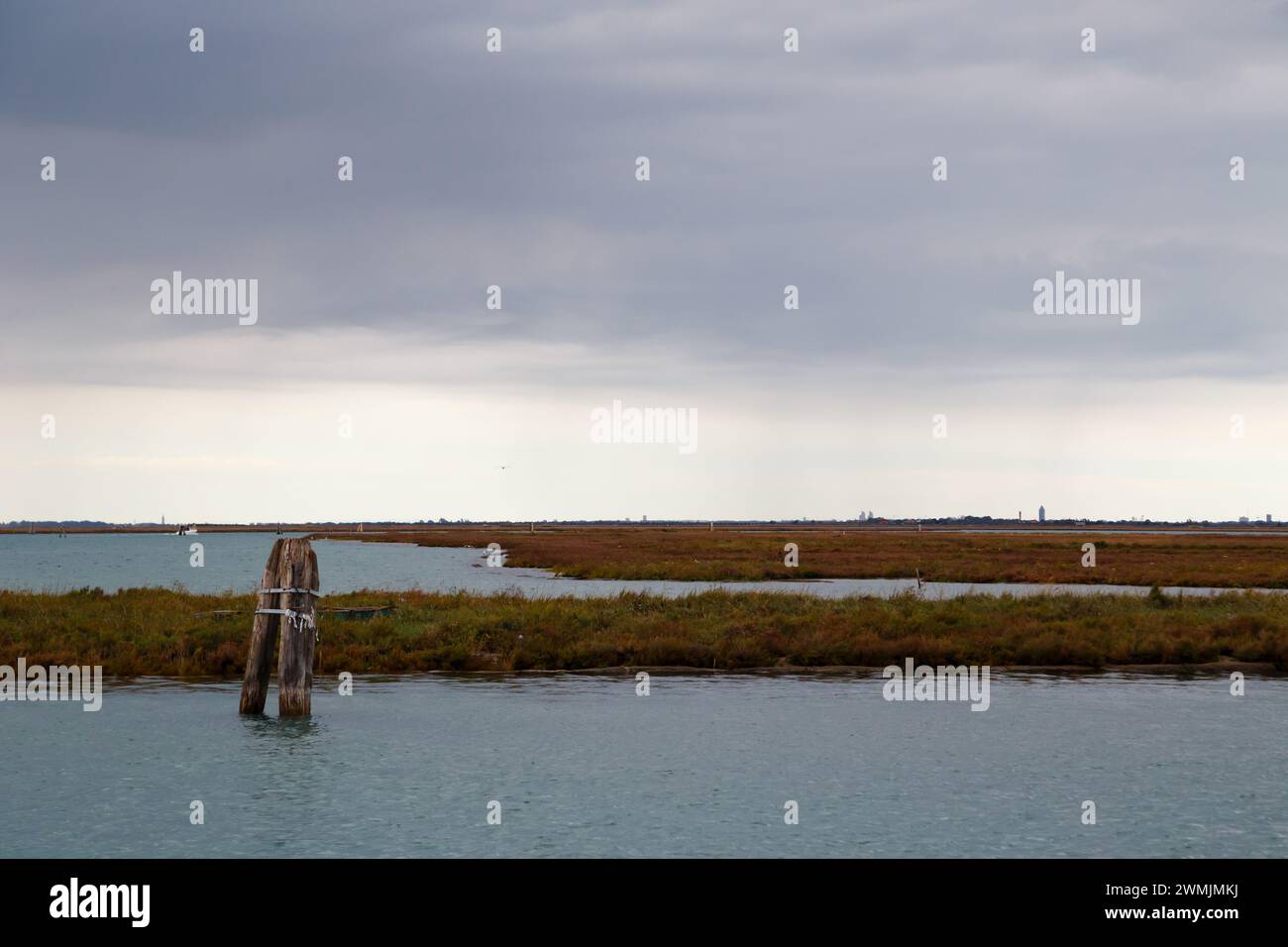 Old mooring post and uninhabited islands of Venetian lagoon. View from Burano island, Venice, Italy. Stock Photo