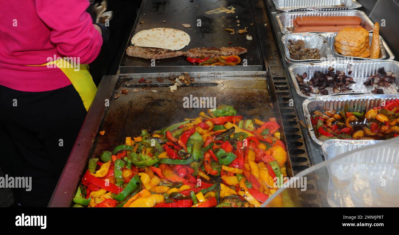 cook of street food truck while preparing the traditional sandwich from North Italy called PANINO ONTO with peppers and  grilled sausage a Stock Photo