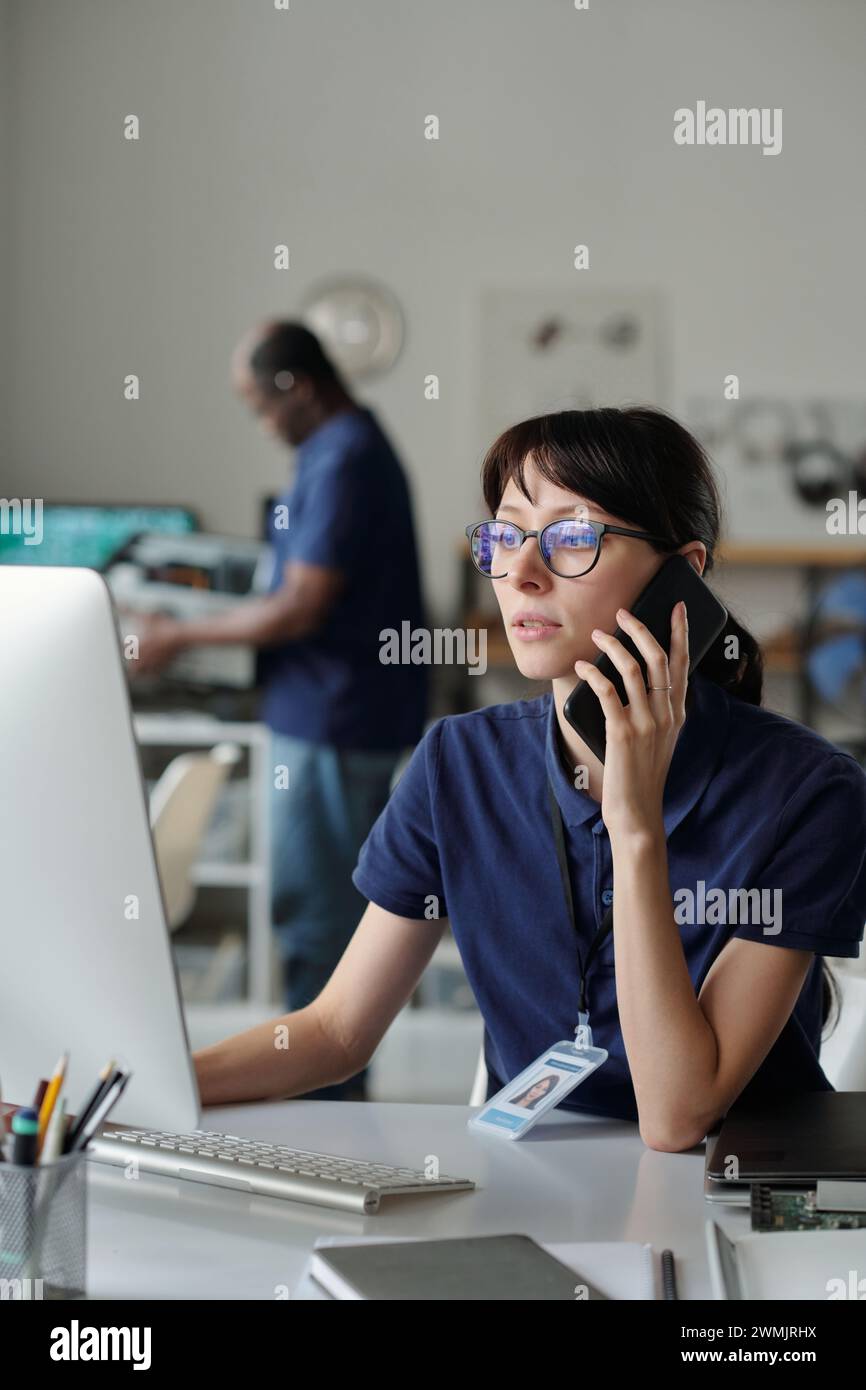 Young confident technician with smartphone by ear communicating to ...