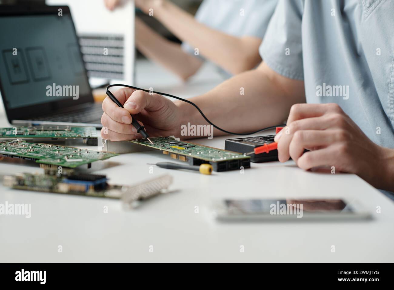 Hands of young worker of troubleshooting service center using electric handtool while checking and repairing computer motherboard Stock Photo