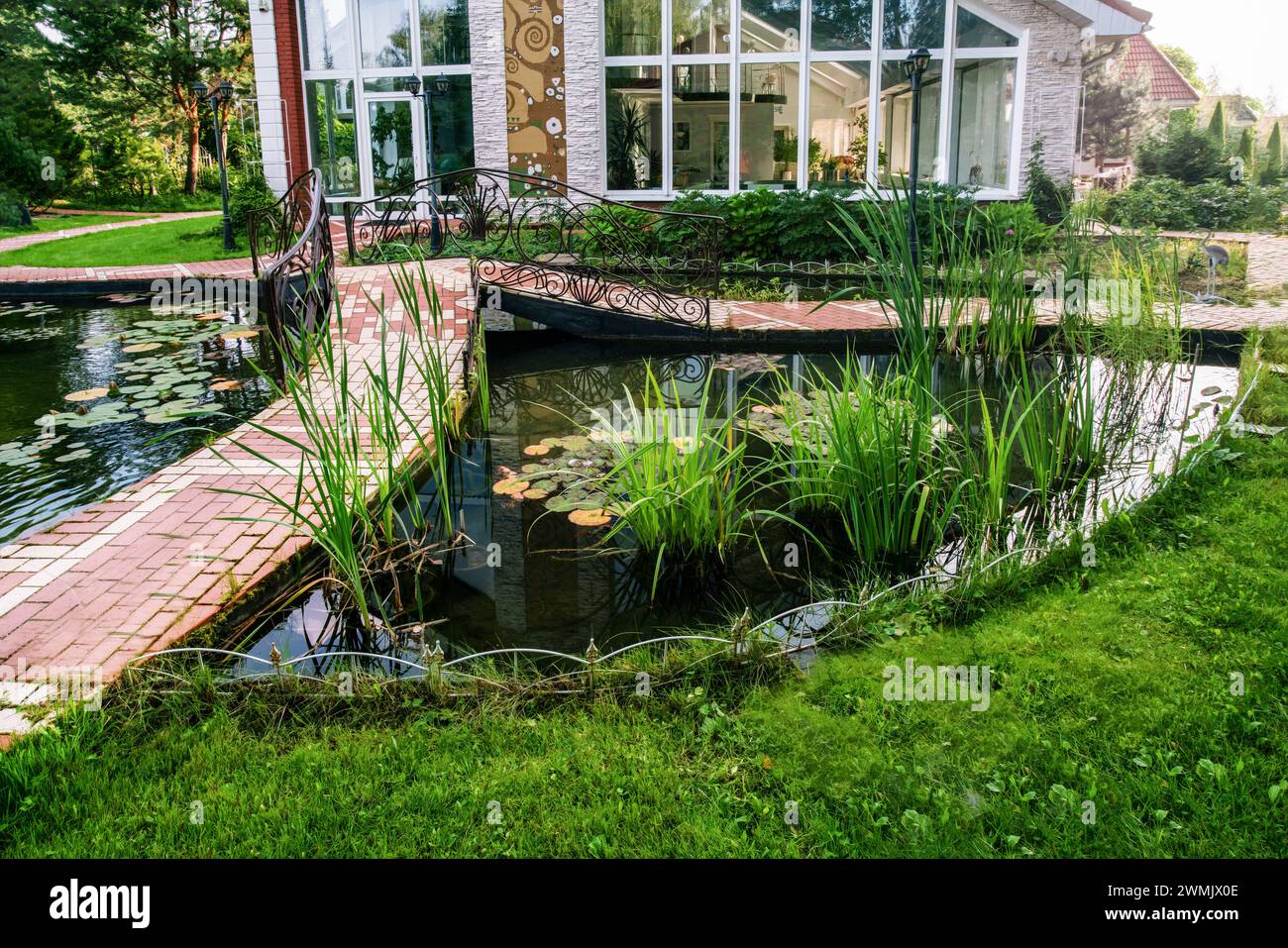 Awe Water Garden  (Pond)next to cottage in prosperous village next to Khimki in  Moscow Oblast with small bridge witg metal railngs Stock Photo