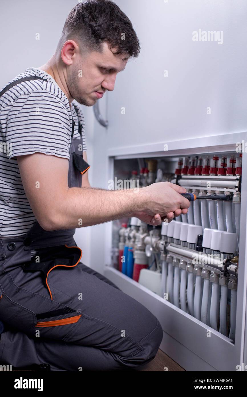 Plumber work. Installing collector for warm water underfloor heating system. Stock Photo