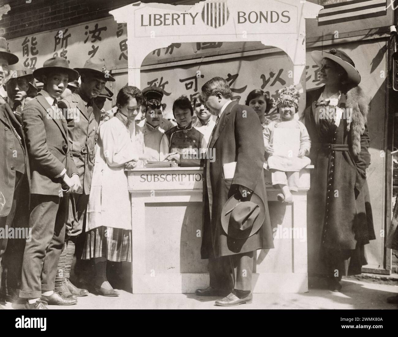 CHINESE GIRLS WORKING FOR THE THIRD LIBERTY LOAN. The daughters of China, an organization composed entirely of young Chinese women residing in New York, have pledged themselves to sell at least $500.00 each of the third Liberty Loan. Miss Ida Lee, the clubleader, is selling Lee Hok, a well known citizen of Chinatown, one of the bonds. Date Taken: 4/26/1918 Stock Photo