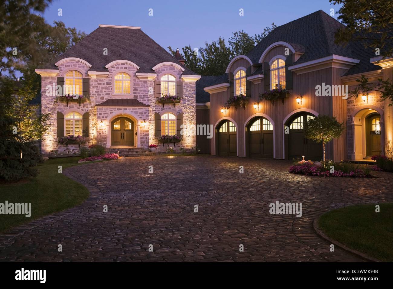 French Manor style natural stone home facade with three car garage and ...