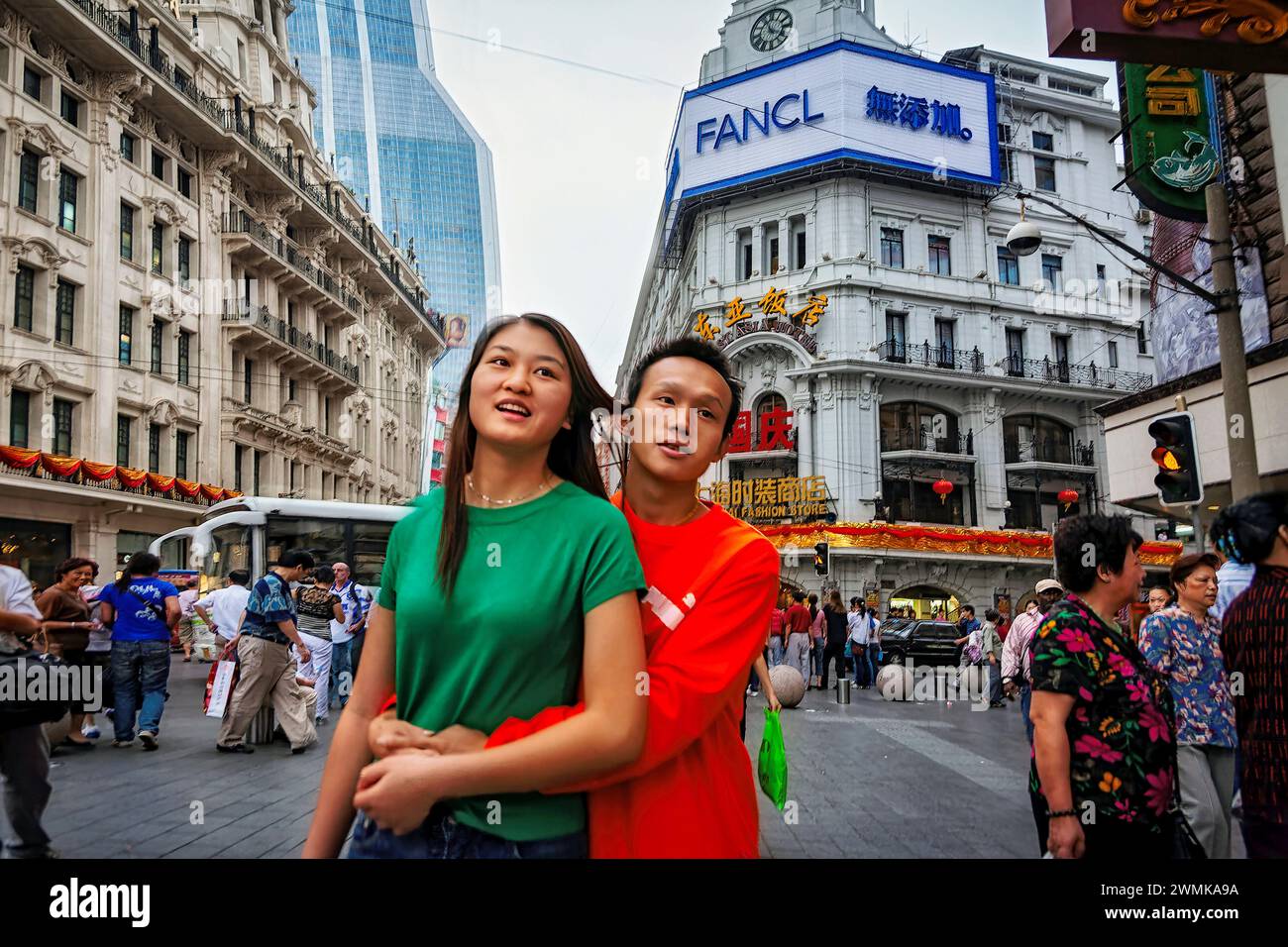Teenage couple standing in an embrace on East Nanjing Road, the world's longest shopping precinct in Shanghai, China. It is around 6 km long and at... Stock Photo