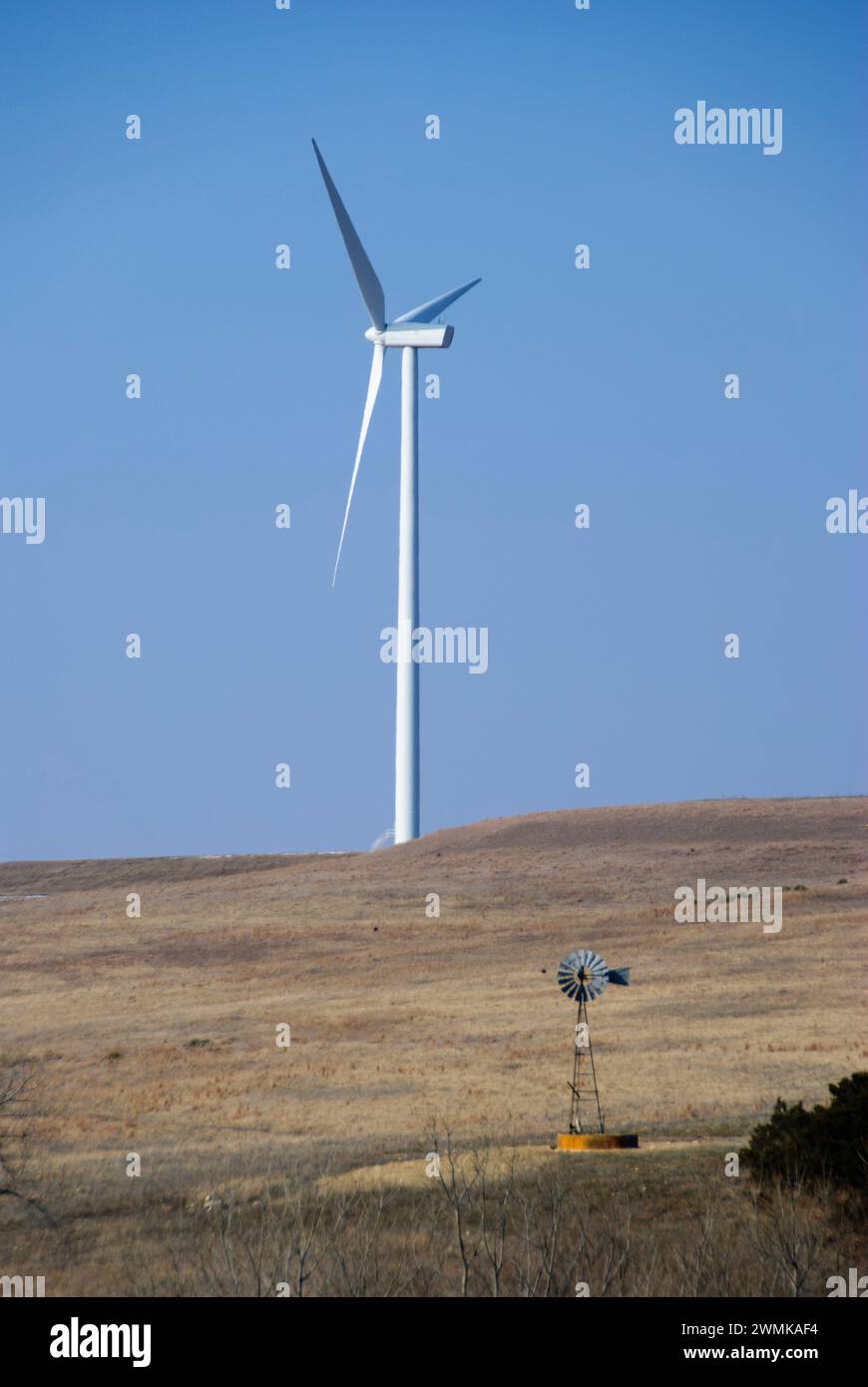 Progress in wind power, a new wind turbine stands towering next to an old windmill Stock Photo