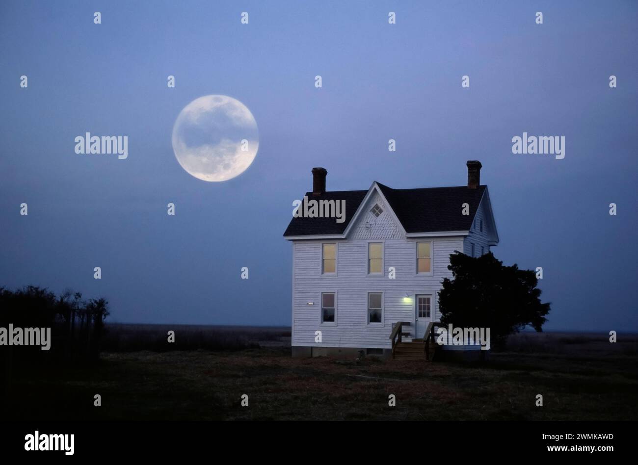 Moonrise over a solitary building on a vast landscape; Crocheron, Maryland, United States of America Stock Photo