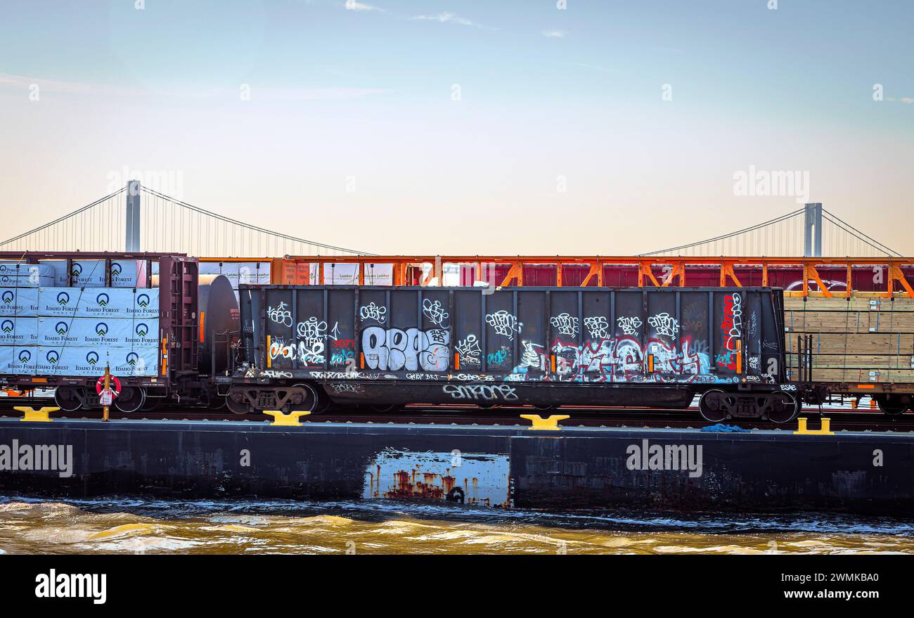 Railroad car and freight on barge, New York Bay with Verrazzano-Narrows Bridge in background, New York City, New York, USA Stock Photo