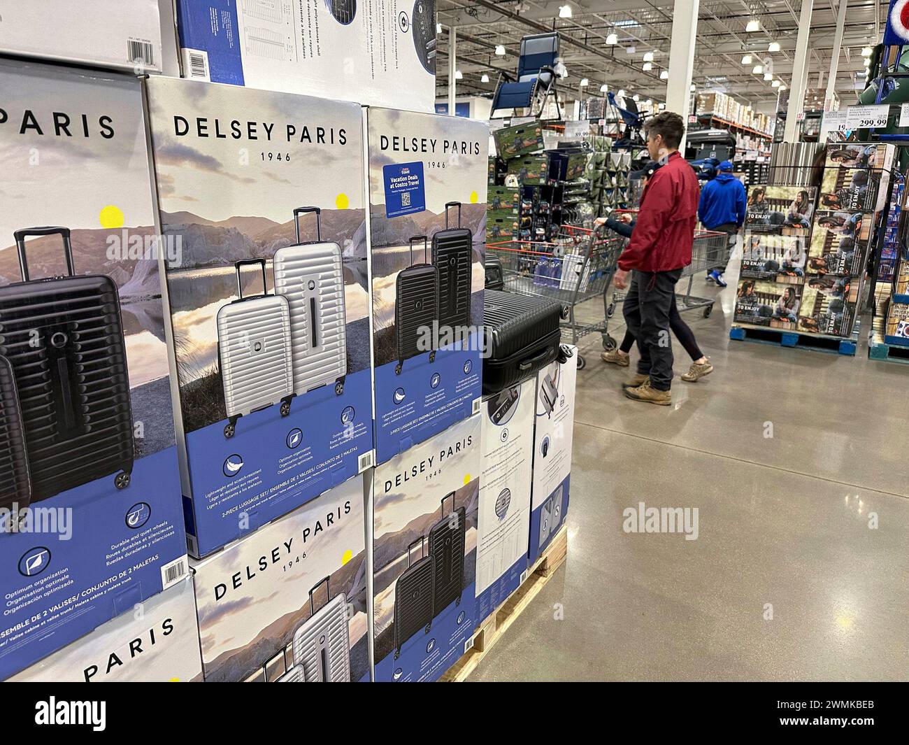 Shoppers glide past a display of baggage in a Costco warehouse Sunday ...