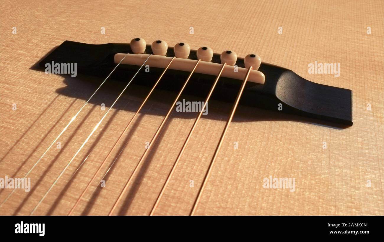 Close up of the bridge on an acoustic steel string guitar Stock Photo