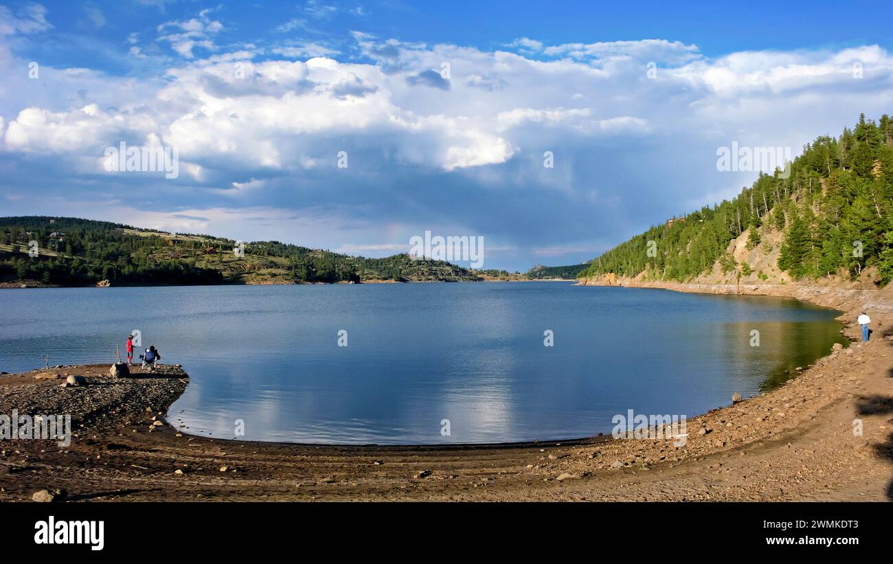 People fishing along the shore of a tranquil lake Stock Photo
