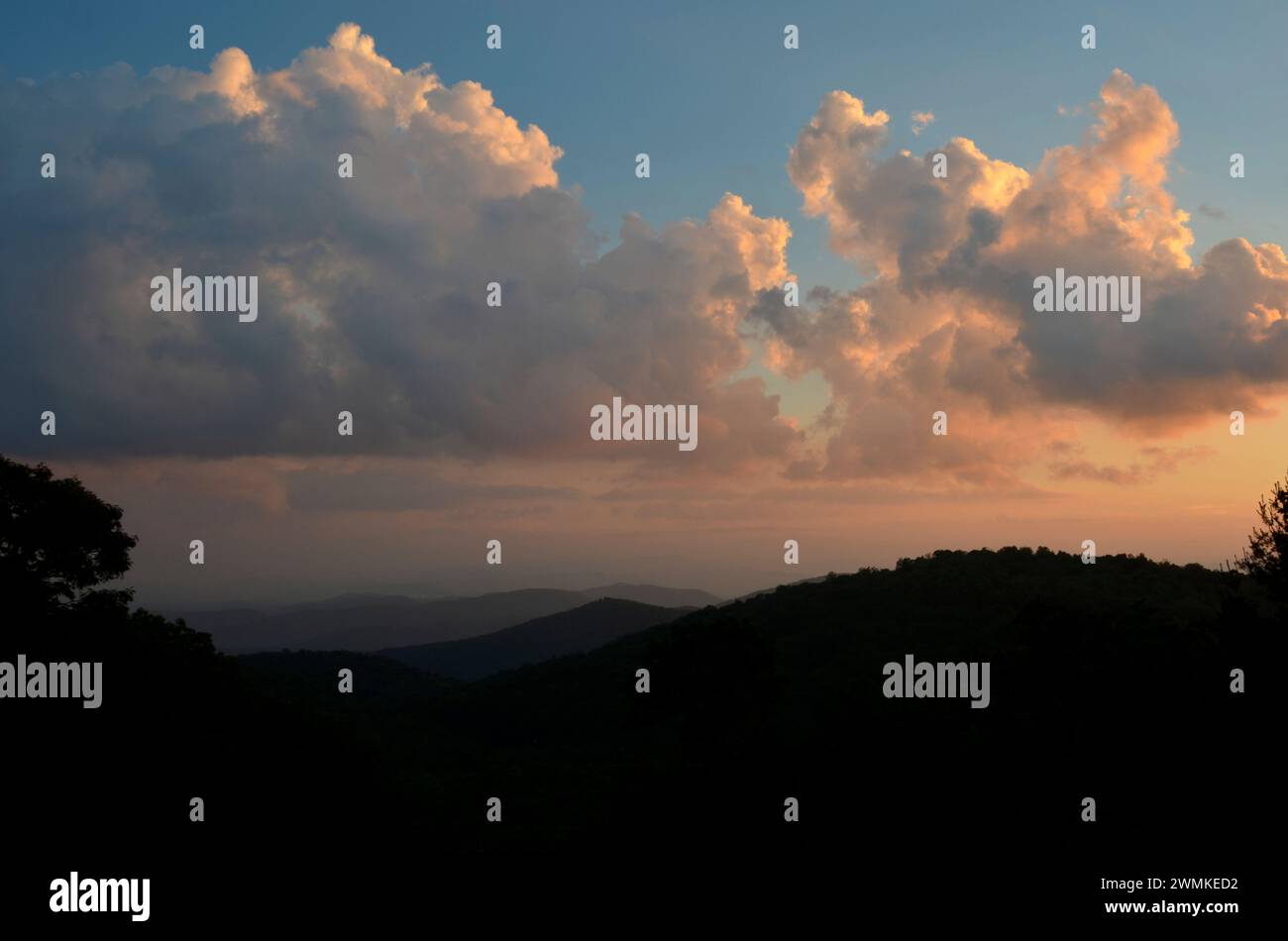 Glowing sunset clouds over silhouetted mountains Stock Photo