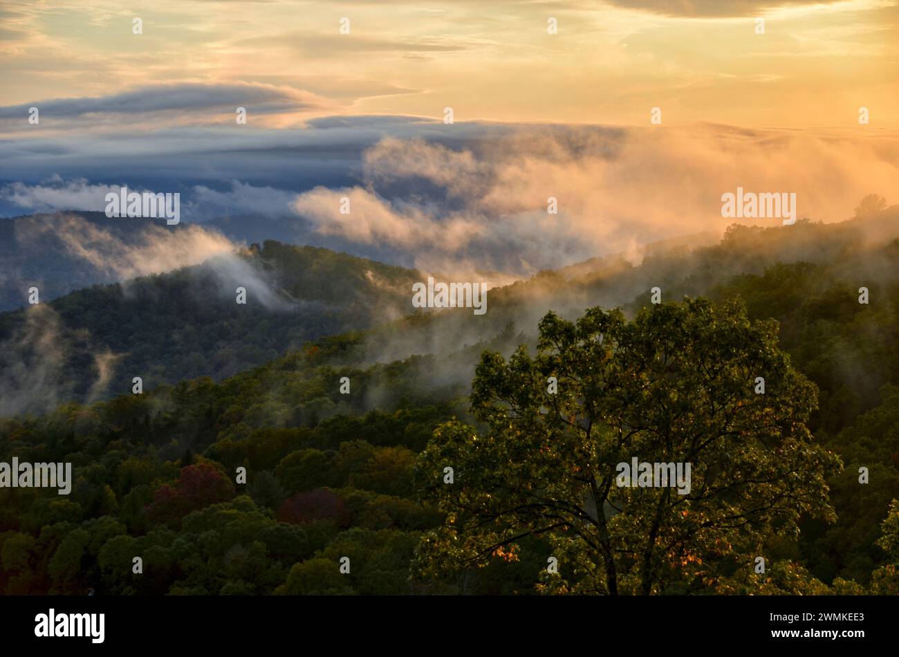 After a storm, clouds and mist roll across the mountains at sunset Stock Photo