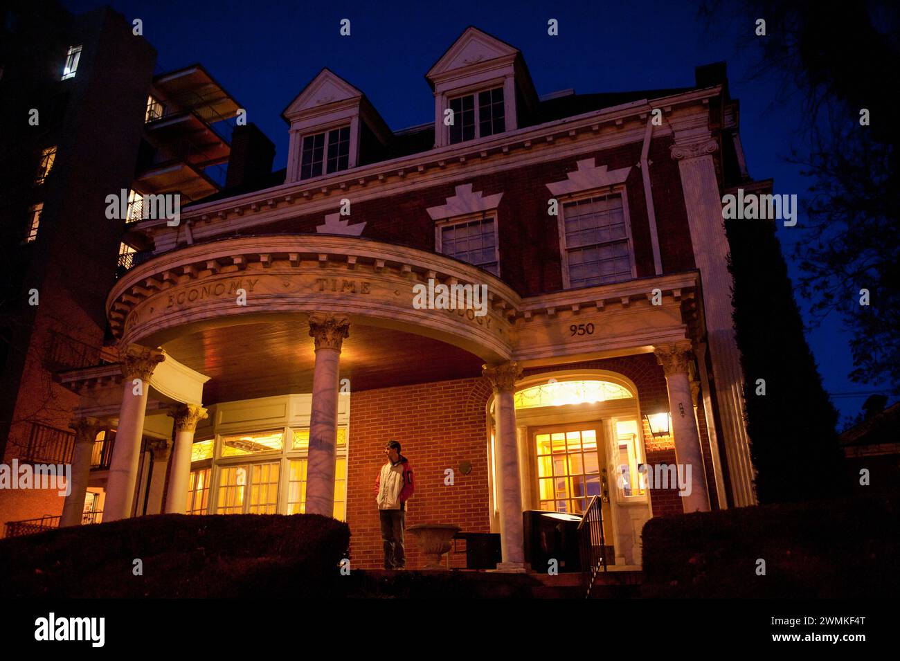 Young man stands outside his home at night; Denver, Colorado, United States of America Stock Photo