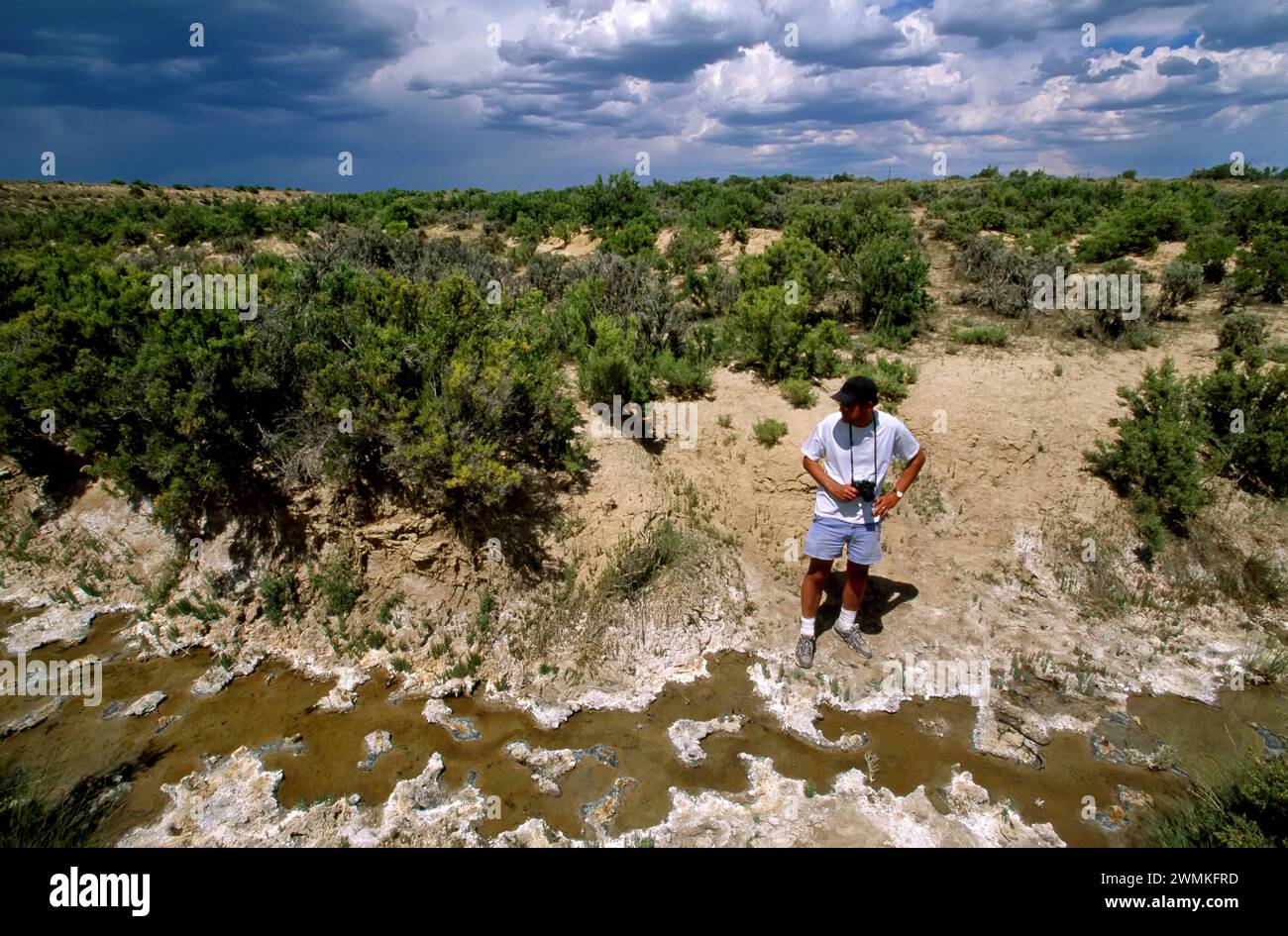 Man looks down on a polluted stream; Wyoming, United States of America Stock Photo