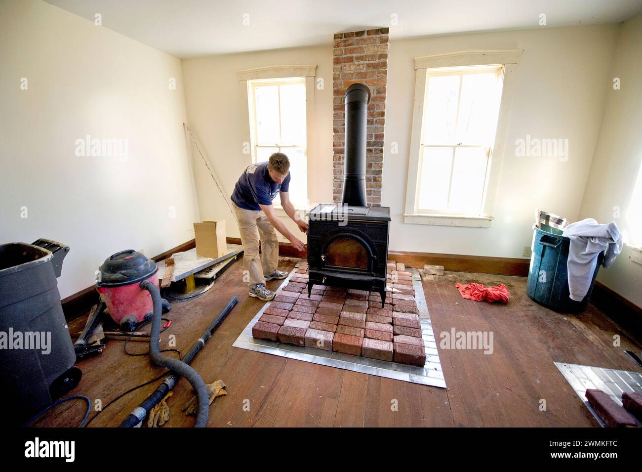 Man works on a wood stove in an old farmhouse; Dunbar, Nebraska, United States of America Stock Photo