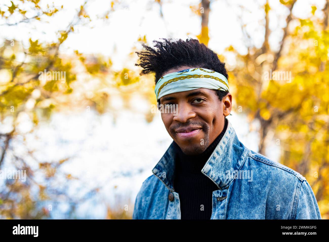 Close-up portrait of a handsome man wearing a bandanna headband, looking at the camera while in a city park in the Fall; Edmonton, Alberta, Canada Stock Photo