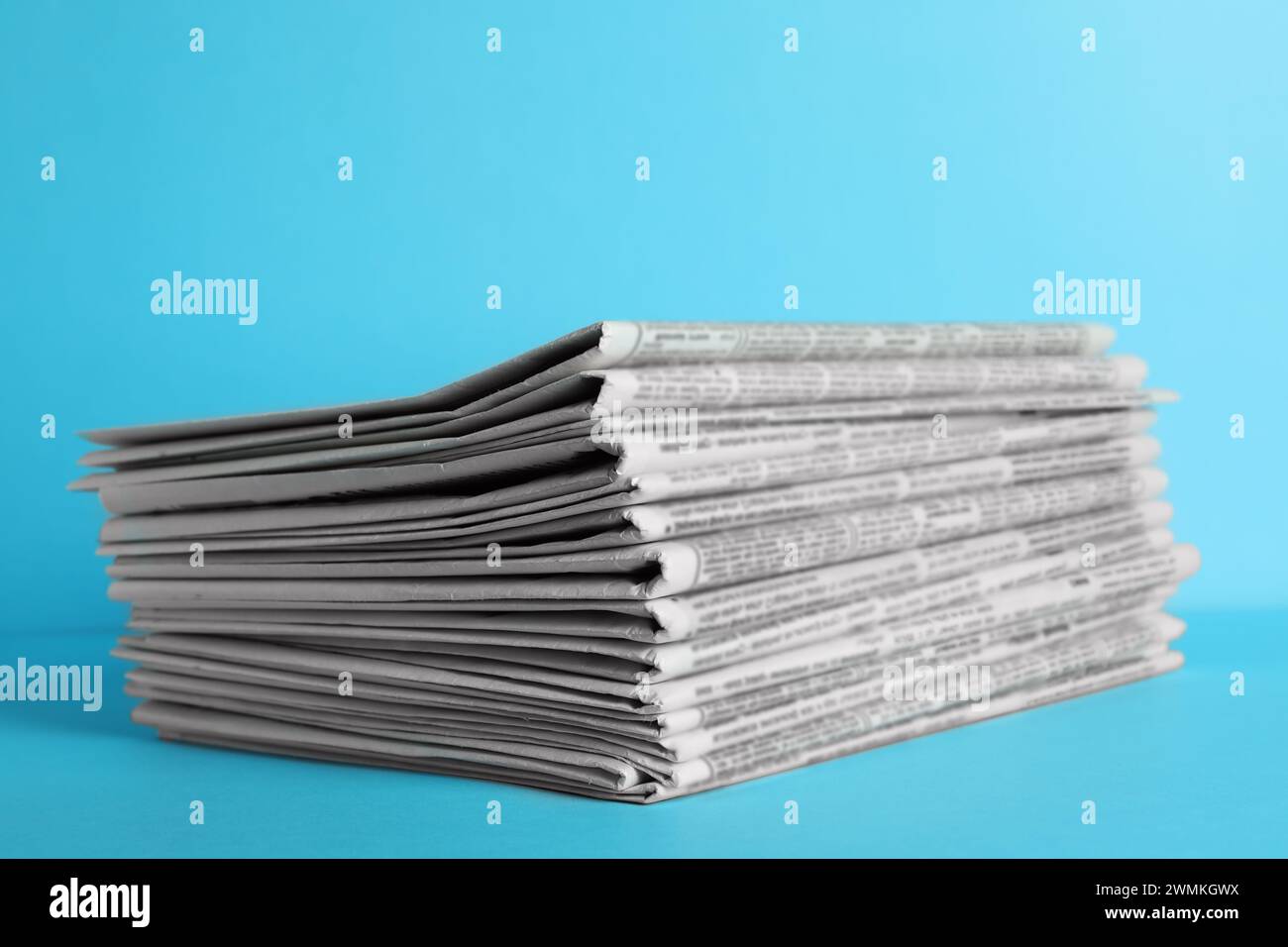 Stack of newspapers on light blue background. Journalist's work Stock Photo