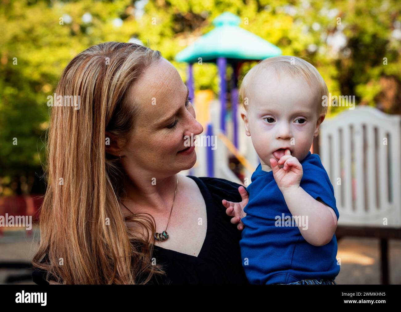 Mother spending quality time with her young son who has Down Syndrome in a city park during an autumn day; Leduc, Alberta, Canada Stock Photo