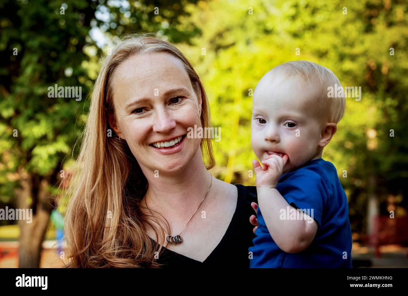 Mother spending quality time with her young son who has Down Syndrome in a city park during an autumn day; Leduc, Alberta, Canada Stock Photo