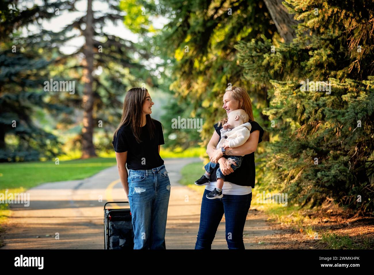 Mother spending quality time with her teenage daughter and young son who has Down Syndrome in a city park during an autumn day; Leduc, Alberta, Canada Stock Photo