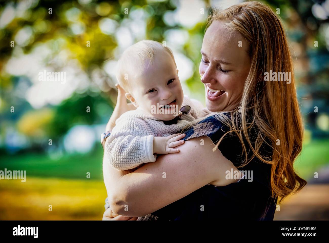Outdoor portrait of a mother spending quality time with her son who has Down Syndrome in a city park during an autumn day; Leduc, Alberta, Canada Stock Photo