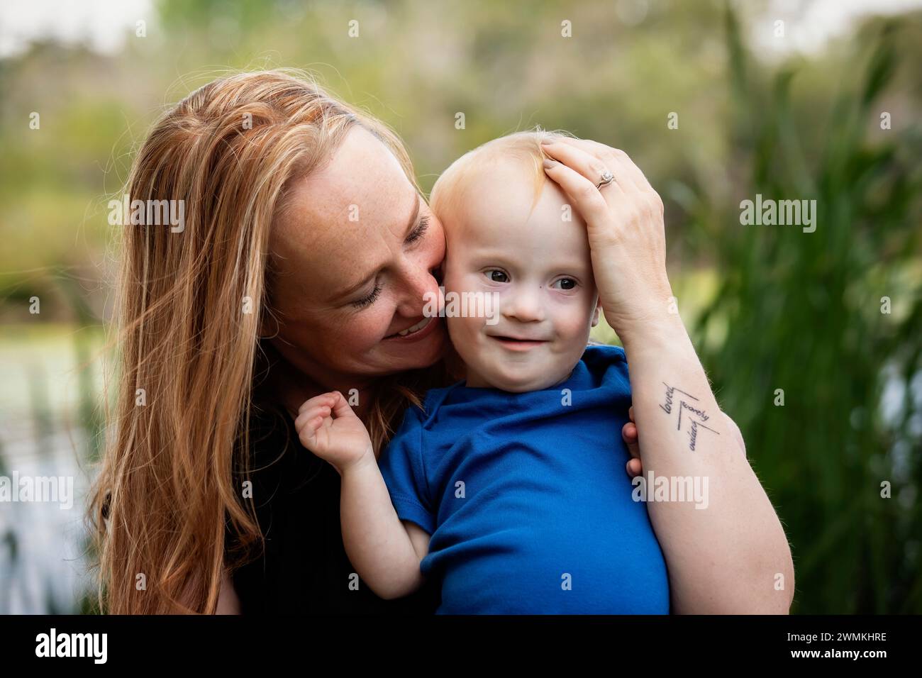 Outdoor portrait of a mother spending quality time with her son who has Down Syndrome in a city park during an autumn day; Leduc, Alberta, Canada Stock Photo