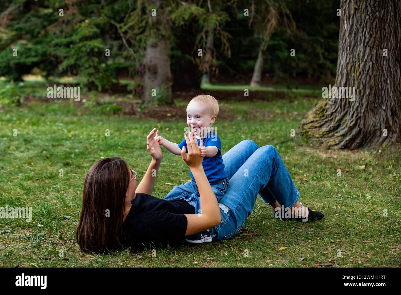 Older sister spending quality time with her young brother who has Down Syndrome, in a city park during a warm fall afternoon; Leduc, Alberta, Canada Stock Photo