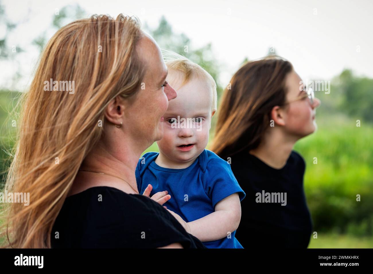 Mother spending quality time with her teenage daughter and young son who has Down Syndrome in a city park during an autumn day; Leduc, Alberta, Canada Stock Photo