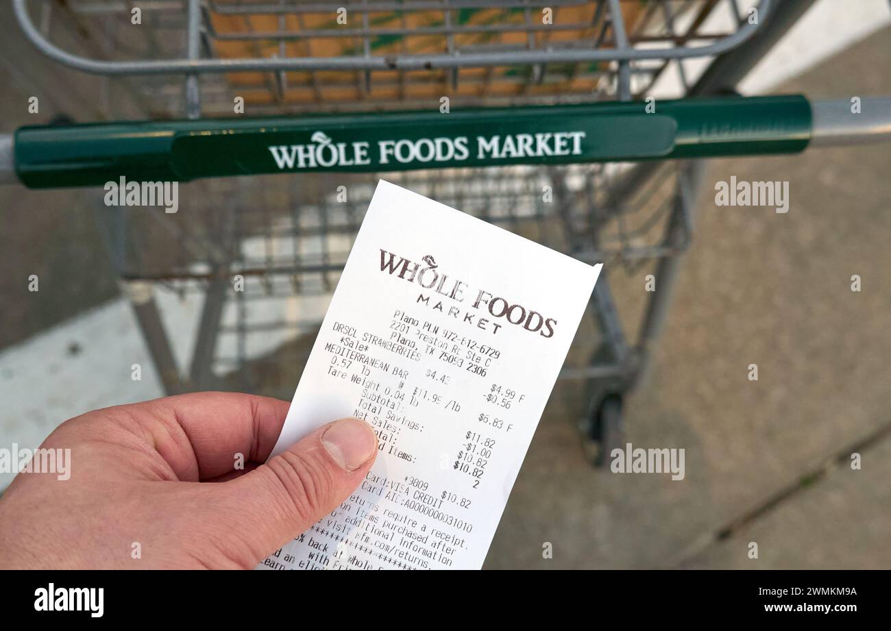 Dallas TX, USA February 25, 2024 A hand holding Whole Foods Market receipt. Owned by Amazon