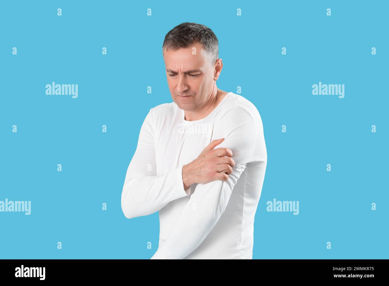 Mature man suffering from shoulder pain on blue background Stock Photo ...