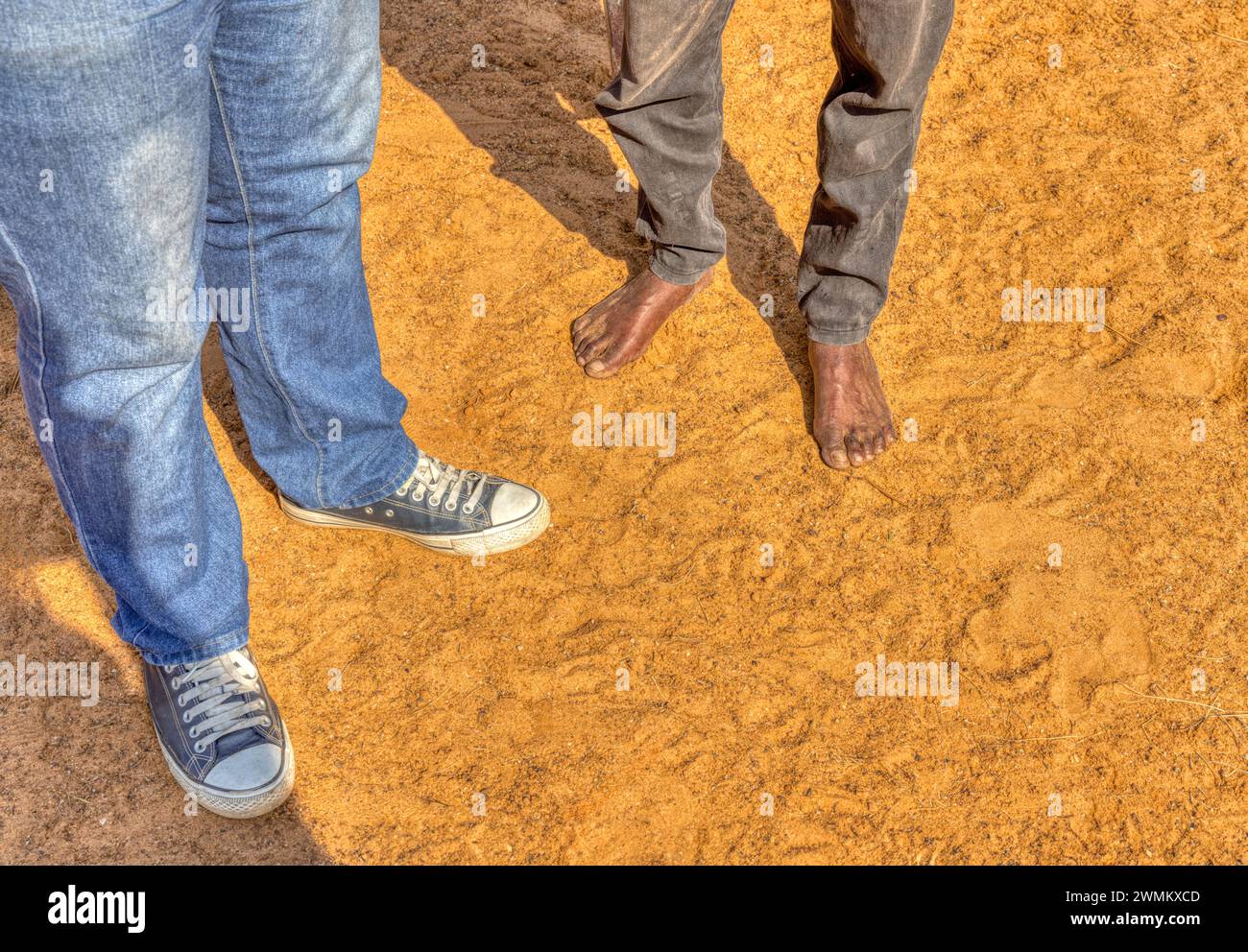 african men feet in the sand one barefoot the other with sneakers Stock Photo