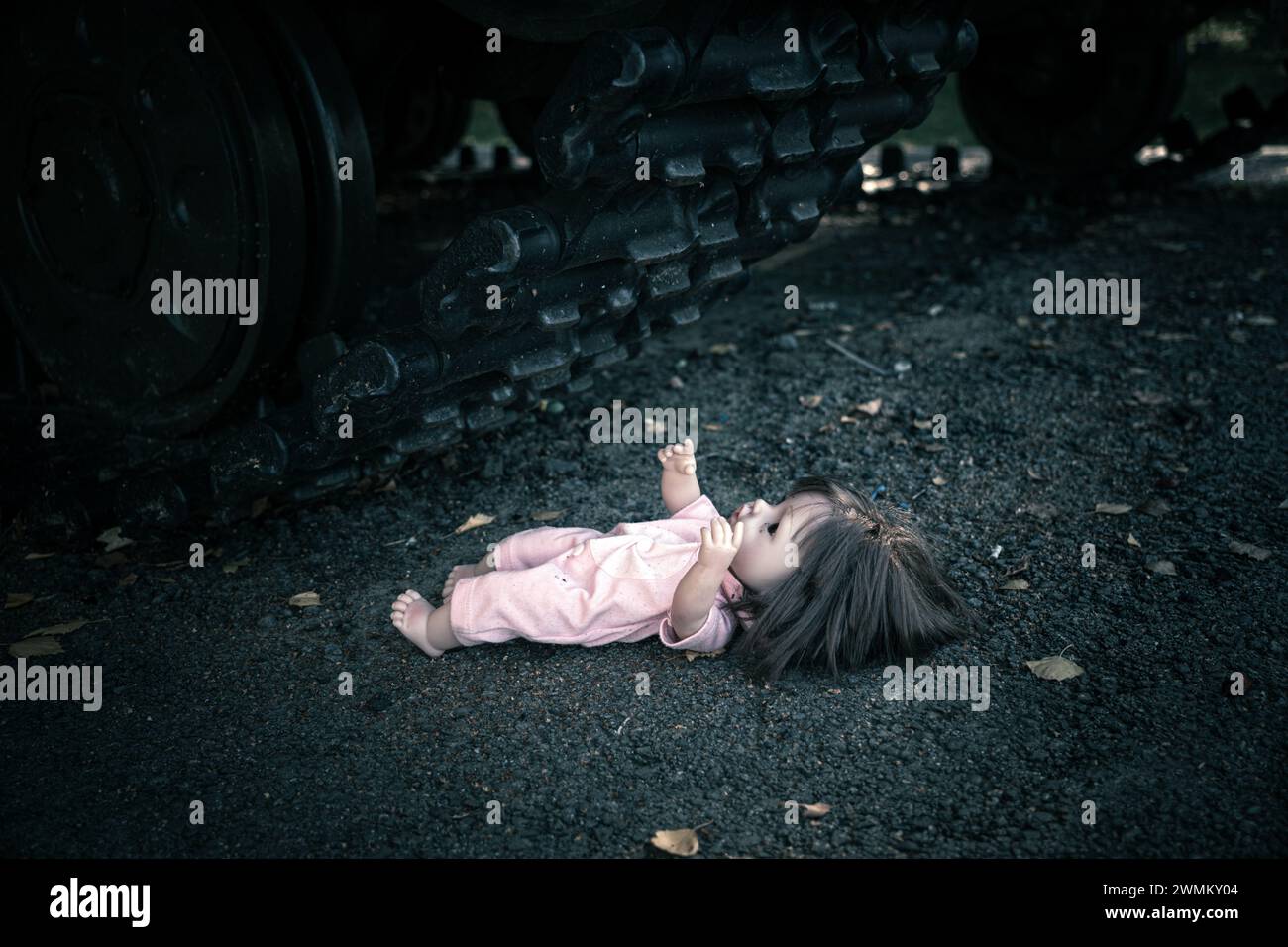 the concept of destroying childhood by war. a frightened doll and tank. the concept of suffering of children and civilians in war. the tank ran over a Stock Photo