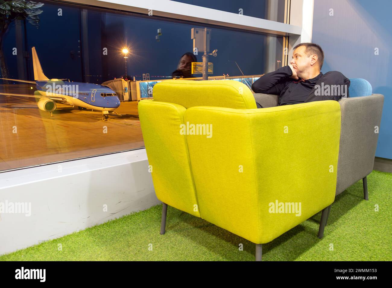 A passenger rests in two displaced chairs for comfort in a night ...