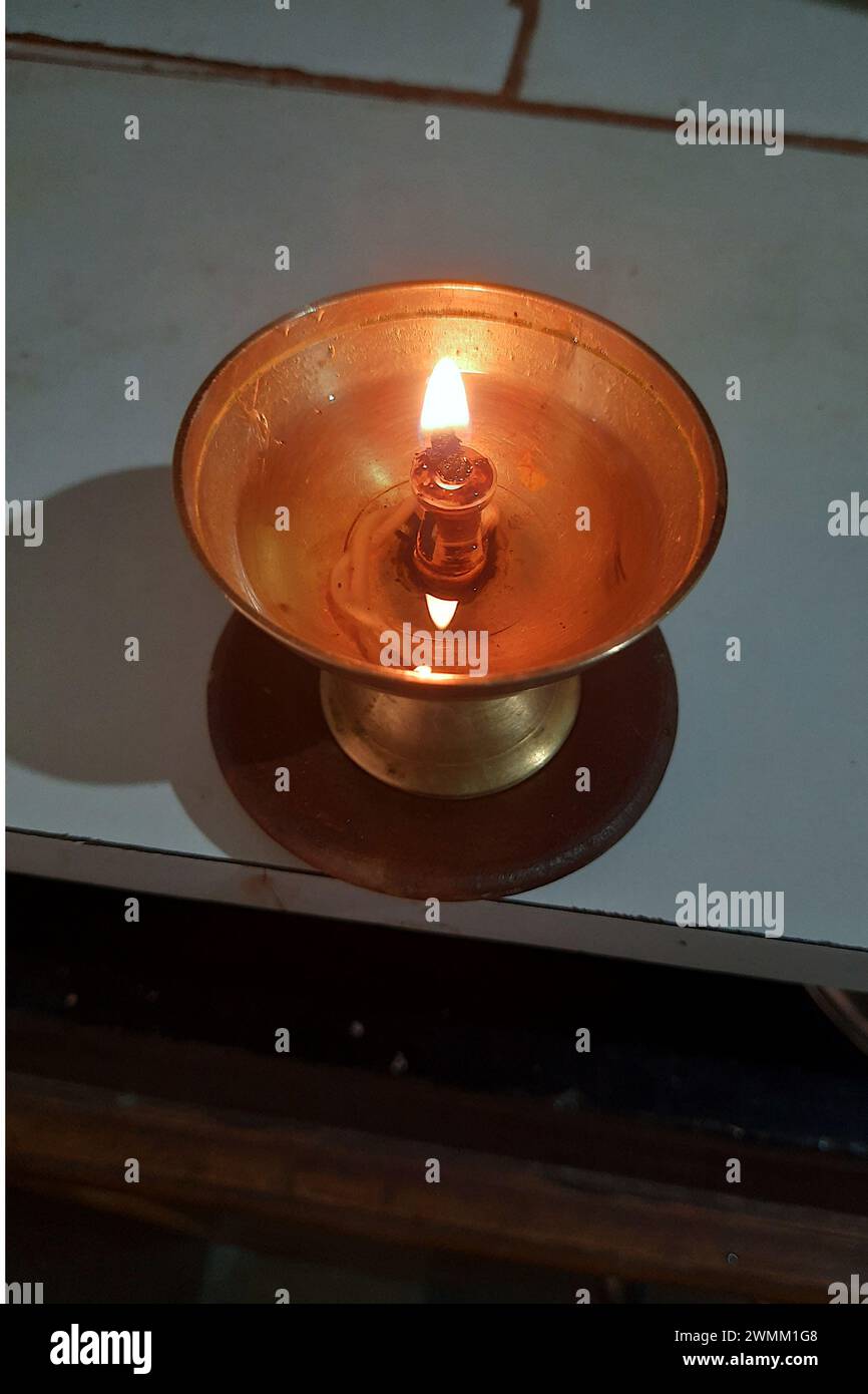 View of lighted, brass oil lamp with oil and cotton wicks used during