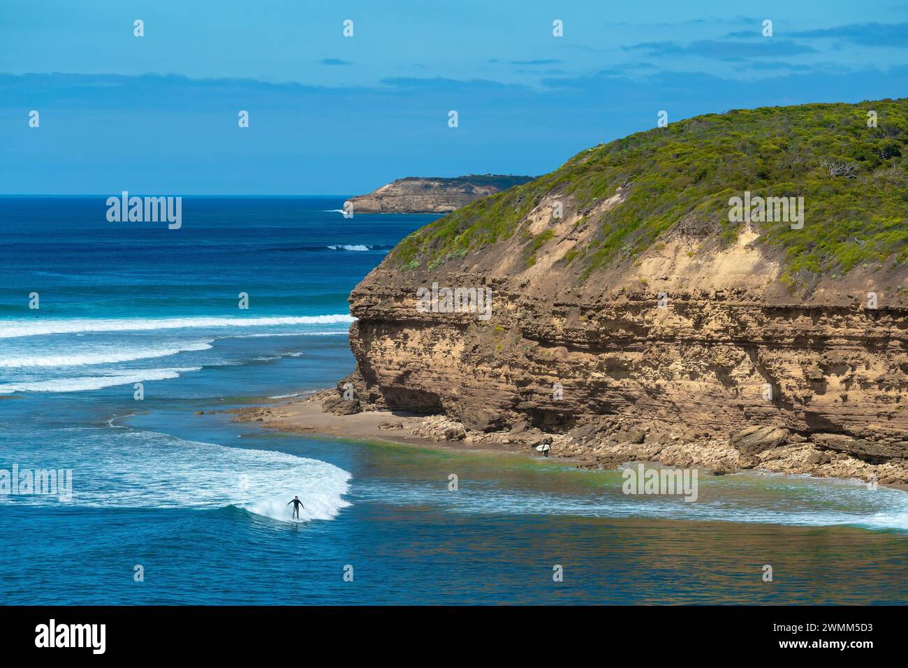 Surfers and the rugged coastline of Bells Beach in Victoria, Australia, seen from Winkipop on the Great Ocean Road. Stock Photo