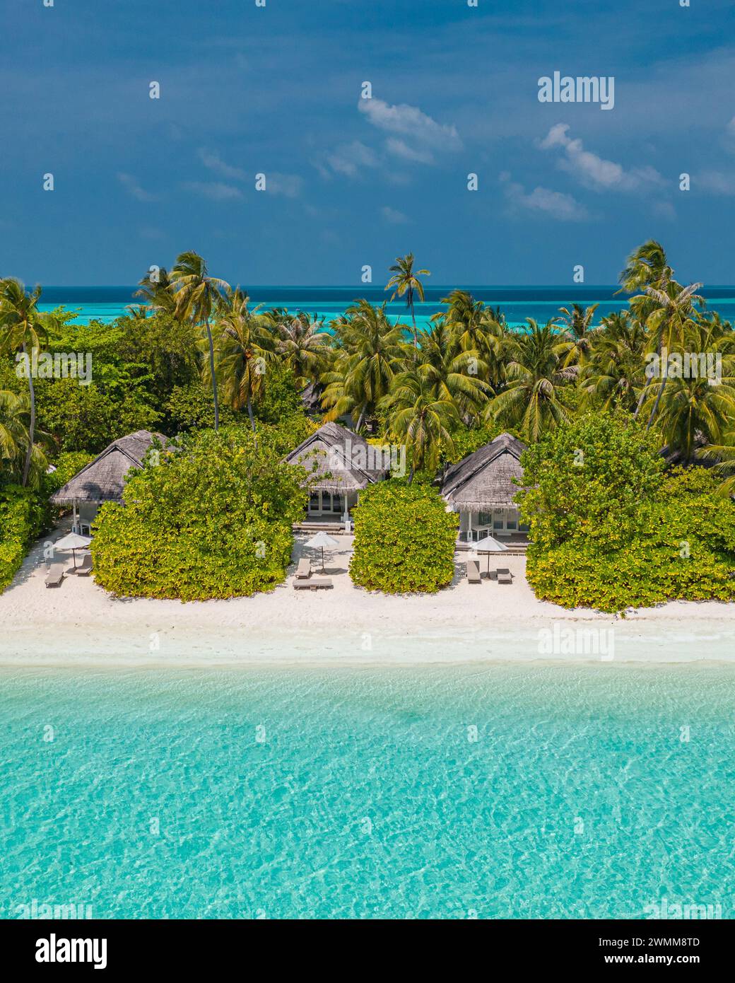 Amazing atoll island in Maldives luxury villas from aerial view. Tranquil tropical landscape seascape. Palm trees white sandy beach, peaceful nature Stock Photo