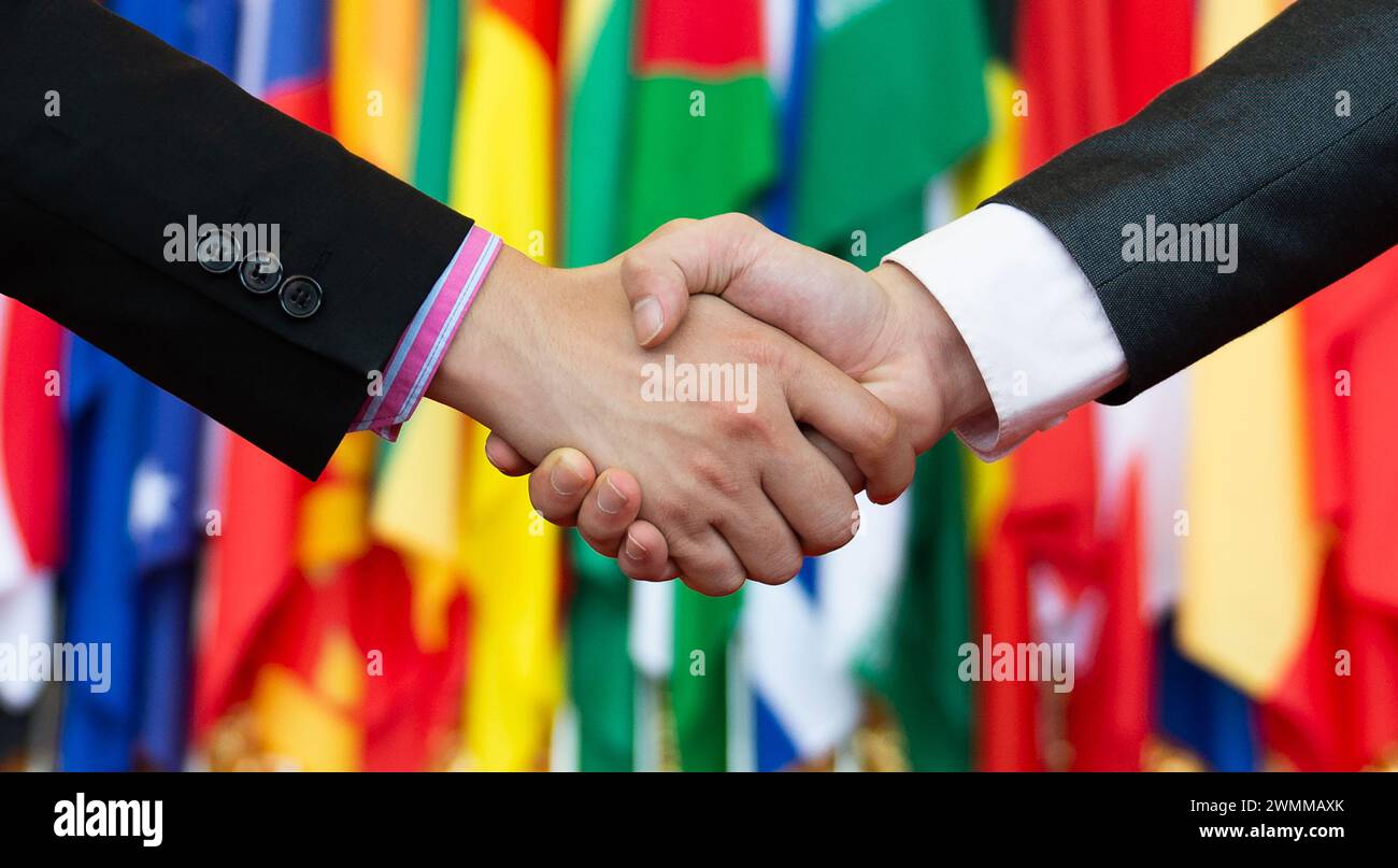 Businessmen shaking hands in front of the multi - national flags Stock ...