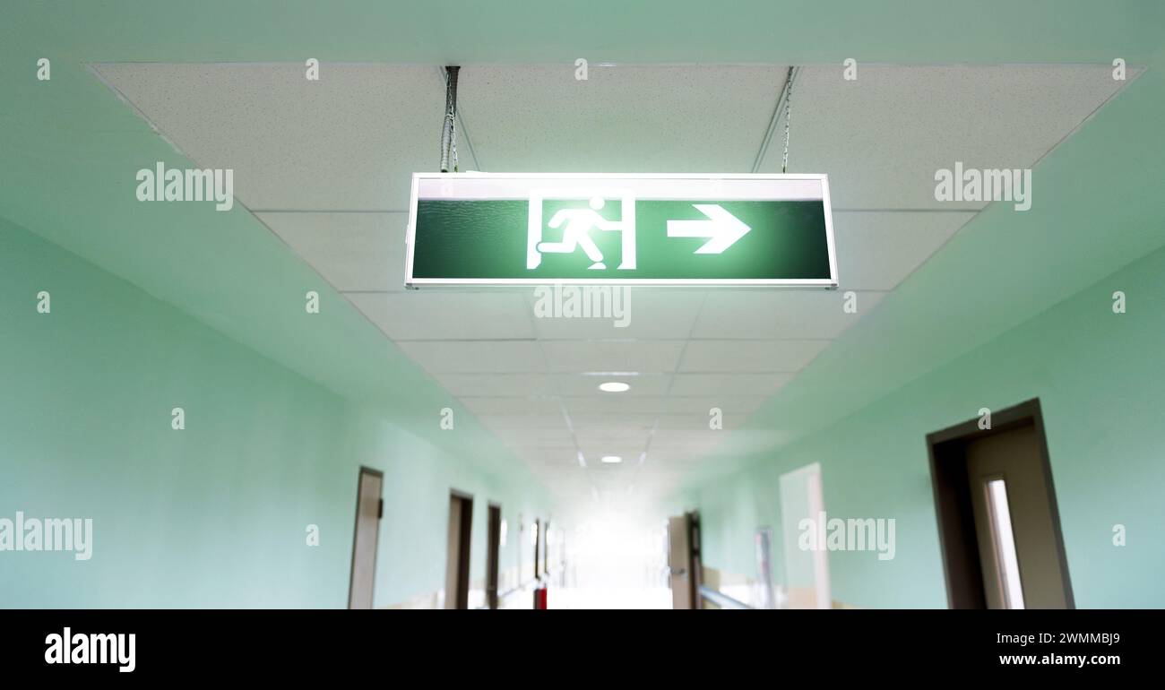 Exit sign suspended from the ceiling of hospital corridor Stock Photo