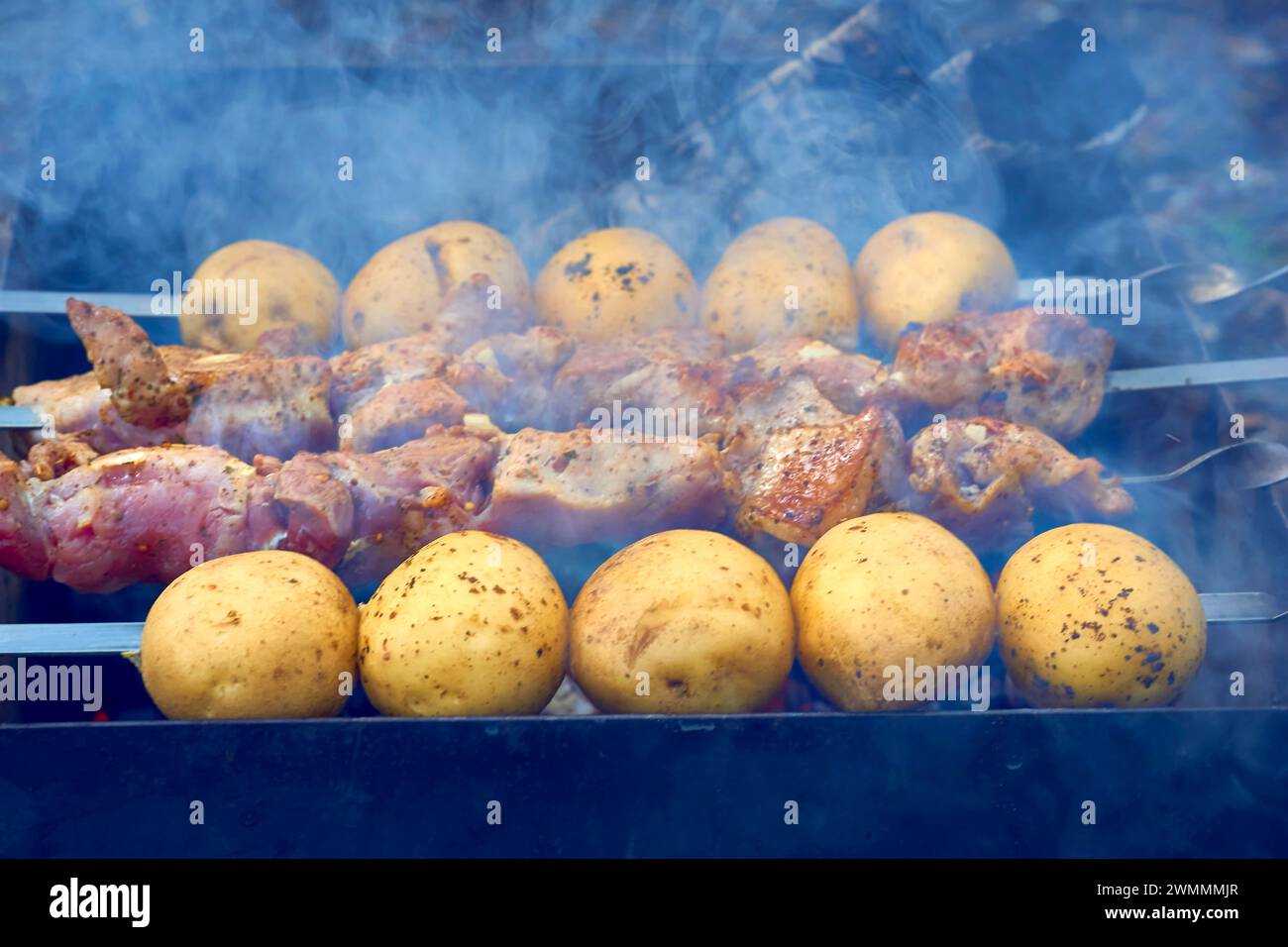 Marinated meat and potatoes on skewers, grilled over hot coal Stock