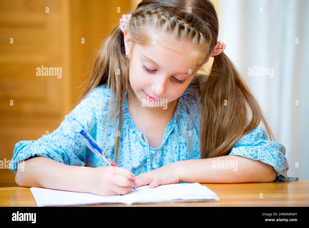 Cute little girl studying at home and smiling Stock Photo - Alamy